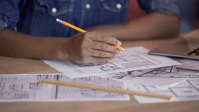 Mixed-race designer working on apartment layout plan, holding pencil, project - Powered by Adobe