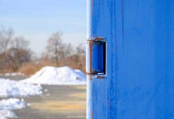 Abstract blue steel door handle. Shipping container handle latch lock. Blue steel rusted industrial wall door. 