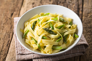 Fresh homemade pasta dish of fettuccine or tagliatelle, green asparagus, garlic and lemon juice in...