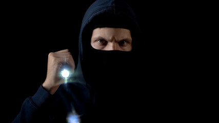 Criminal in balaclava flashing torch to break lock, forced entry, breaking in