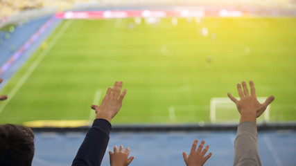 Male and kid stretching hands up at stadium, cheering for football team victory