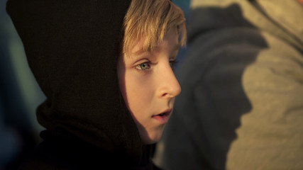 Fototapeta premium Lonely boy in hoodie sitting outdoor, bullying victim, humiliation at school