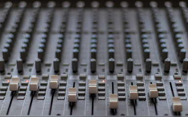 Front view of mixing console with sliders and red lights