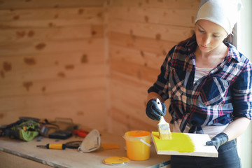 Woman with brush repair in a wooden house