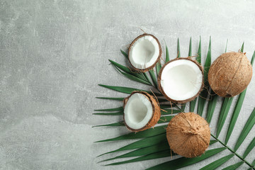 Fototapeta na wymiar Fresh coconuts with palm branch on grey background, space for text