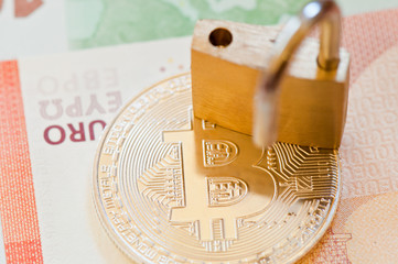Golden Bitcoin and the lock (close-up). Cryptocurrency. Euro banknote background