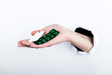 Female hand out of the hole in the paperman, holding blisters with pills. Isolate on white background.