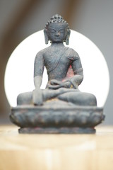 Statue or figurine of sitting black indian buddha on wooden floor on white background