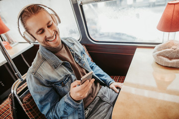 Cheerful male in headphones look in smartphone