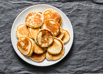 Heap of mini pancakes on a gray background, top view. Delicious breakfast, brunch, dessert