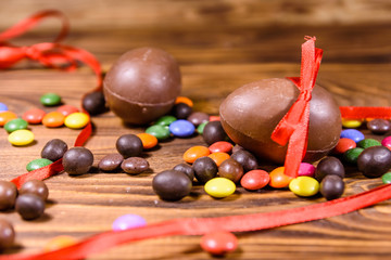 Chocolate easter eggs and multicolored candies on wooden table