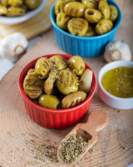 Wooden background with green olives, olive oil, garlic and spices