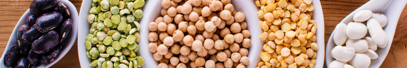 Various assortment of legumes - beans, soy beans, chickpeas, lentils, green peas. Top view banner format