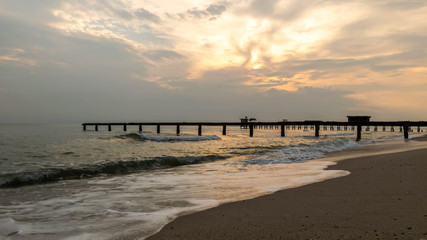 Obraz premium Old stone bridge into the sea and Sea waves is in the foreground.
