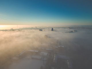 thick fog over the city in the rays of the rising sun