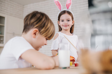 Obraz na płótnie Canvas Smiling little girl with bunny ears on head looking ar camera