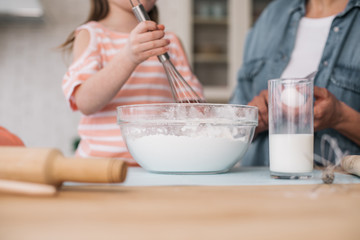 Bowl with dough and glass of milk situating on table