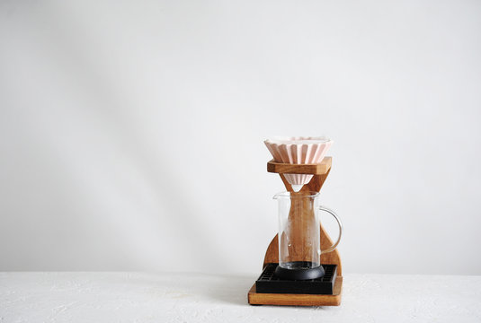 Alternative manual coffee brewing. Pink ceramic origami dripper. Wooden stand. Light background. Free space for text