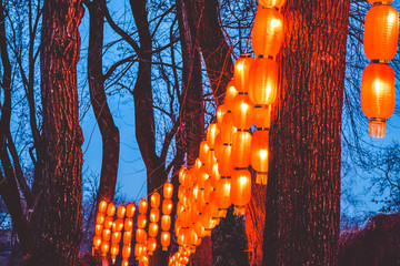 Tapes on trees in the park from the Chinese orange small lamps. The lit street at night. Lighting.