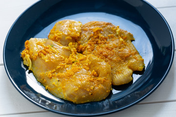 Raw, flavored with turmeric, basil and oregano chicken fillet on a plate.