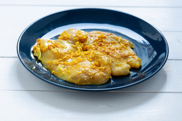 Raw, flavored with turmeric, basil and oregano chicken fillet on a plate.