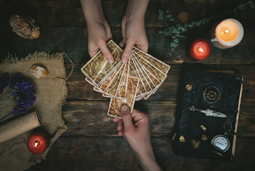 Tarot cards, magic book and fortune teller hands on a wooden table background. Future reading concept. Divination. © Dmitriy