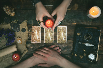 Tarot cards, magic book and fortune teller hands on a wooden table background. Future reading...