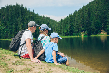 family sitting at beach of mountains lake