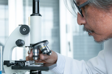 Close up scientist looking through a microscope in a laboratory.