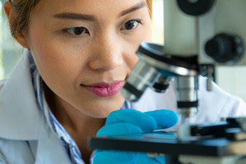Close up scientist looking through a microscope in a laboratory. Science technology research and development concept