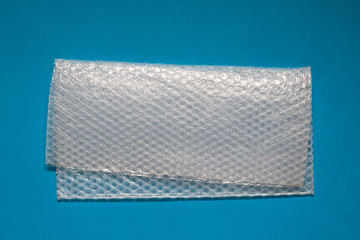 Bubble wrap on blue background. Bubble wrap is a pliable transparent plastic material used for packing fragile items.