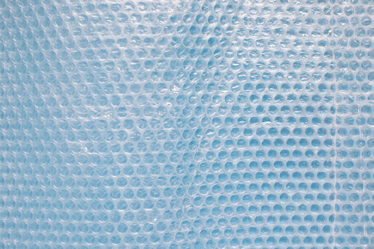 Bubble wrap on blue background. Bubble wrap is a pliable transparent plastic material used for packing fragile items.
