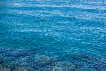vivid blue water tropic nature background surface with blurred glares from sun and transparent thick, copy space