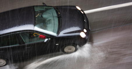 Rainy day in the city: A driving car in the street hit by the heavy rain with hail in motion blur - 255785732