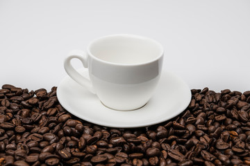 White ceramic cup on the roasted coffee beans background