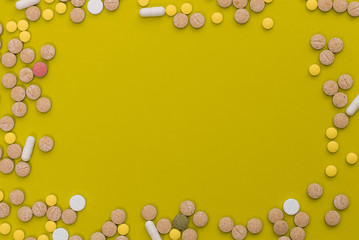 Medical colorful pills, capsules or supplements for the treatment and health care on yellow background. Creative idea. Drugs. Sad. Die. Illness.