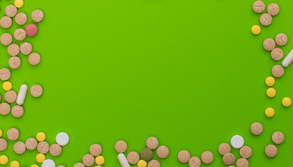 Medical colorful pills, capsules or supplements for the treatment and health care on green background. Creative idea. Drugs. Sad. Die. Illness.