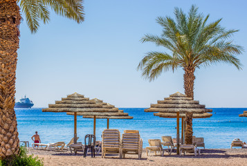 luxury summer vacation beach of Red sea coast line in Israel Middle East country post card vivid colorful concept photography with furniture palm trees and resting people