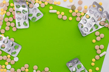 Medical colorful pills, capsules or supplements for the treatment and health care on green background. Creative idea. Drugs. Sad. Die. Illness.