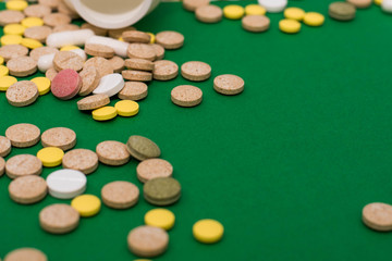 Medical colorful pills, capsules or supplements for the treatment and health care on green background. Creative idea. Drugs. Sad. Die. Illness.