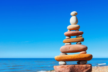 Rock zen pyramid of colorful pebbles on a beach on the background of the sea. Concept of balance, harmony and meditation.