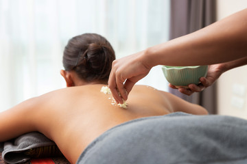 Obraz premium Asian woman enjoying a salt scrub massage at spa.
