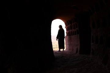 MAN WITH ROBE AND PALESTINIAN SCARF AT THE ENTRANCE OF A CAVE