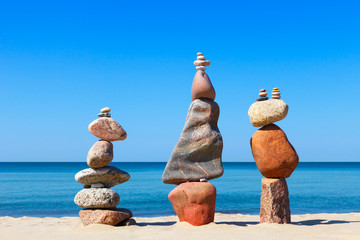 Fototapeta na wymiar Three Rock zen pyramids of colorful pebbles standing on the beach, on the background of the sea. Concept of balance, harmony and meditation.