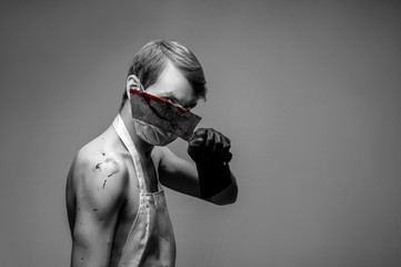 man in a bathrobe covers his face with a knife, knife in of blood, black and white photography