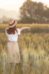 Beautiful asian woman having fun at barley field in summer at sunset time