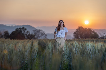 Beautiful asian woman having fun at barley field in summer at sunset time