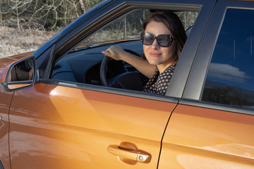 A independent woman sitting behind the wheel of her suv smiling and looking at camera. The concept...