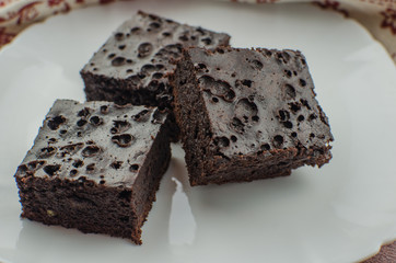 Sliced homemade brownies on white plate. Served on rectangle white plate. Favorite chocolate dessert for chocolate lover. Sweet and moist of cocoa taste. Top view.