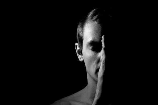 Dramatic portrait of a guy on a black background, black and white photography